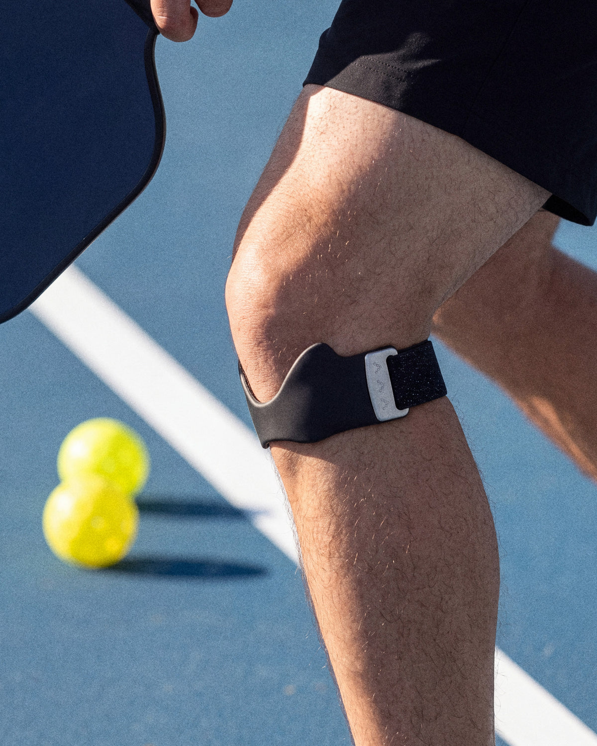 Close-up of the Second Set strap worn below the kneecap at the kitchen line of a pickleball court