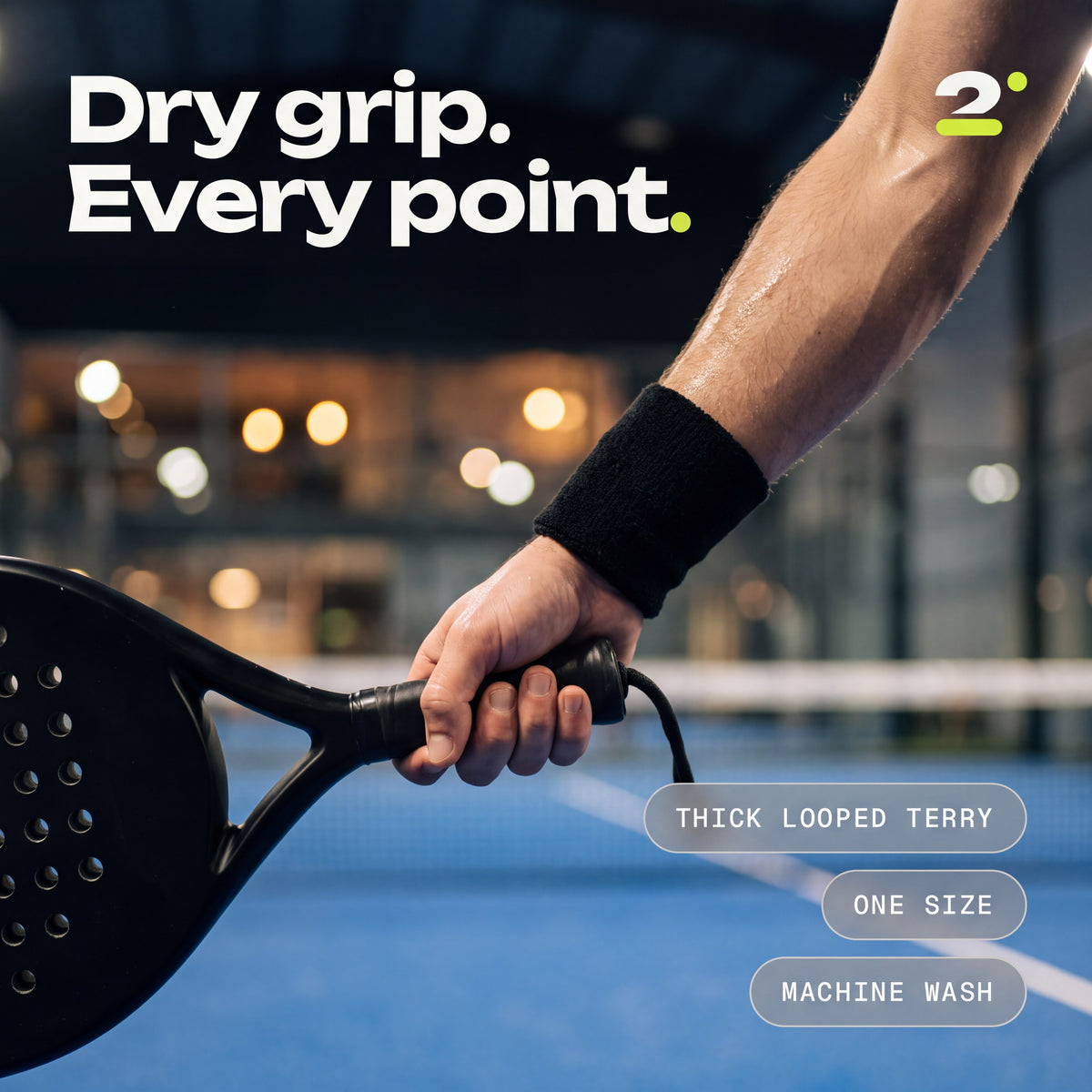 A player's wrist in an Ink sweatband, gripping a padel racket. Dry grip. Every point.